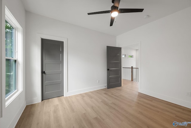 unfurnished bedroom featuring light wood finished floors, baseboards, and ceiling fan