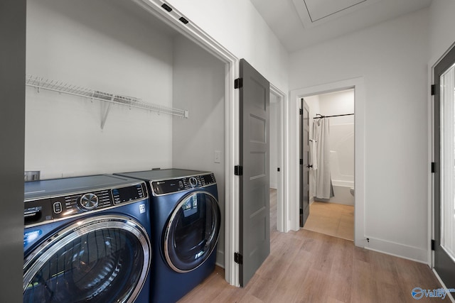 laundry room with washer and clothes dryer and light wood-style flooring