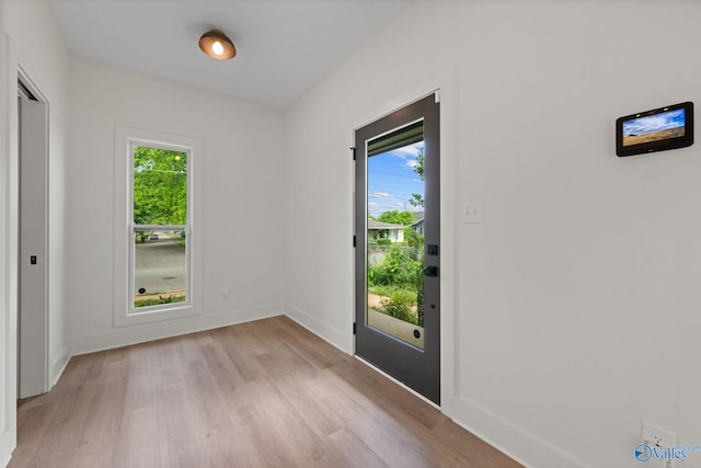 doorway featuring light wood-type flooring, plenty of natural light, and baseboards