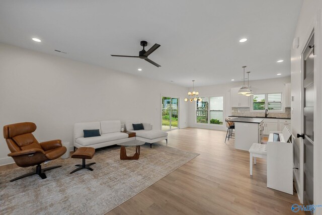 living area with light wood finished floors, recessed lighting, a ceiling fan, a chandelier, and baseboards