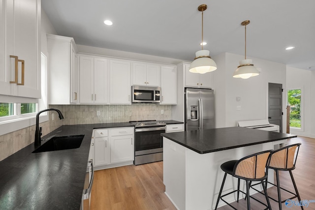 kitchen featuring stainless steel appliances, a sink, tasteful backsplash, dark countertops, and recessed lighting