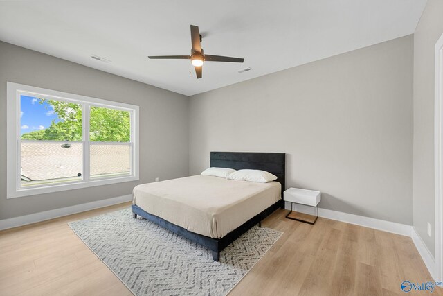 bedroom featuring baseboards, light wood-style flooring, and a ceiling fan