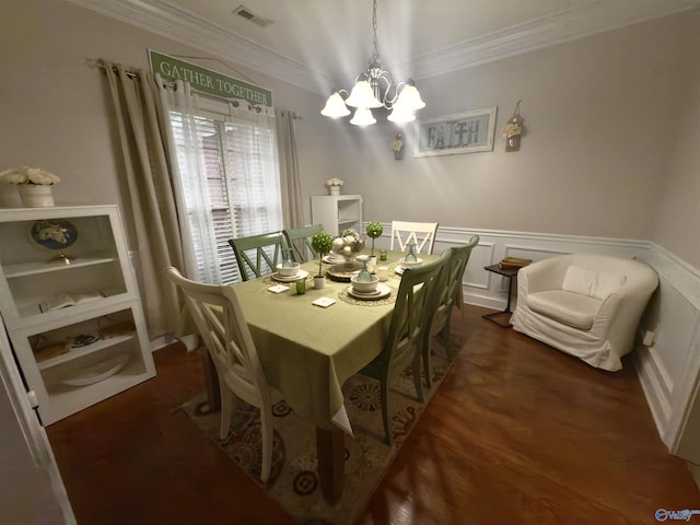 dining space with a notable chandelier, a wainscoted wall, visible vents, ornamental molding, and wood finished floors