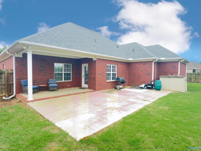 back of house with fence, roof with shingles, a patio area, and a yard