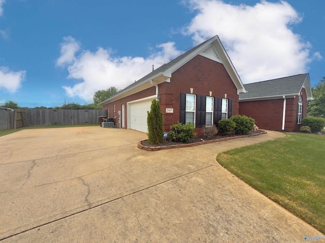 view of home's exterior featuring driveway, a lawn, fence, brick siding, and a garage