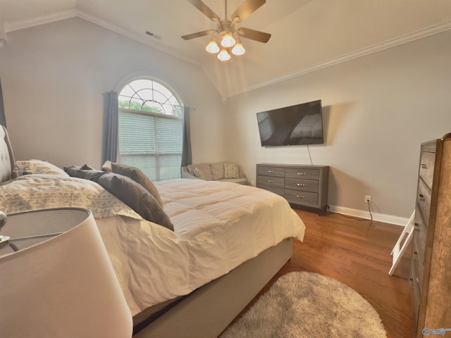 bedroom with wood finished floors, crown molding, vaulted ceiling, and baseboards