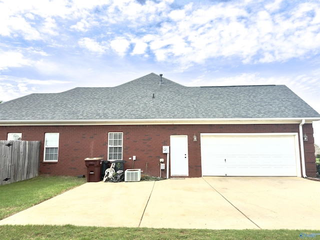 rear view of house with fence, an attached garage, driveway, and roof with shingles
