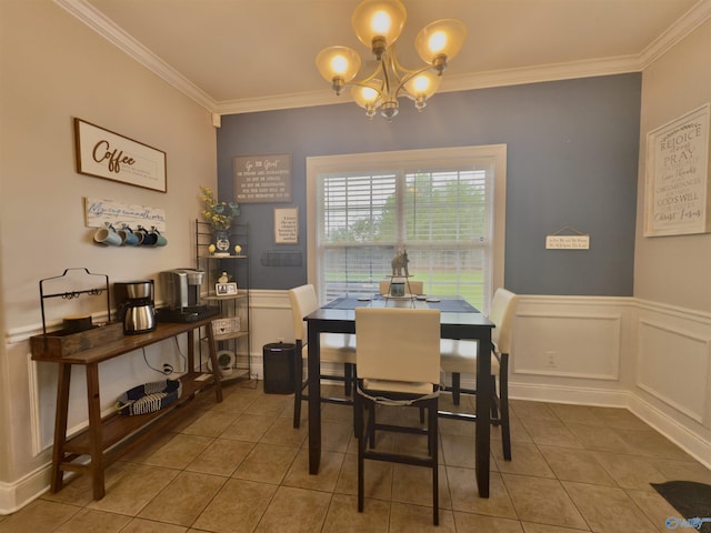 dining space with tile patterned floors, an inviting chandelier, crown molding, and wainscoting