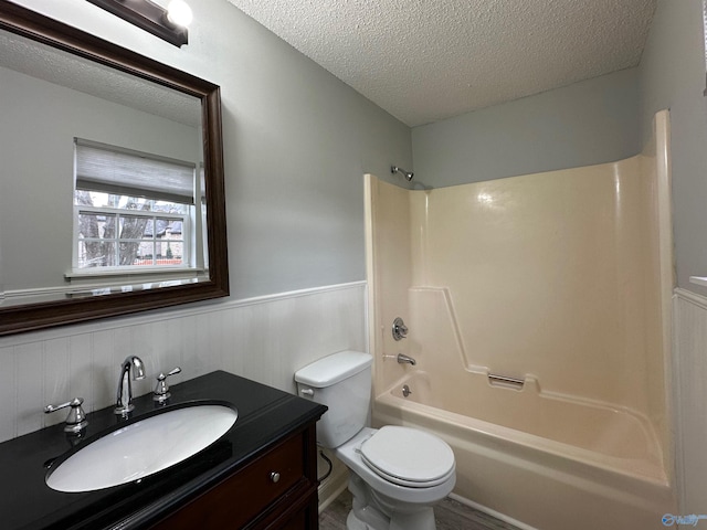 full bathroom featuring vanity, tub / shower combination, toilet, and a textured ceiling