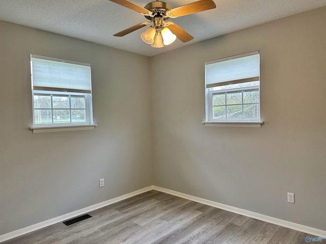 empty room featuring a textured ceiling, light hardwood / wood-style flooring, and a healthy amount of sunlight