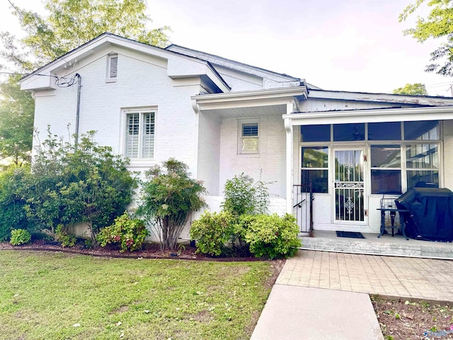 102 Jackson St, Albertville, AL 35950 - view of front facade with brick siding, a front lawn, and a sunroom