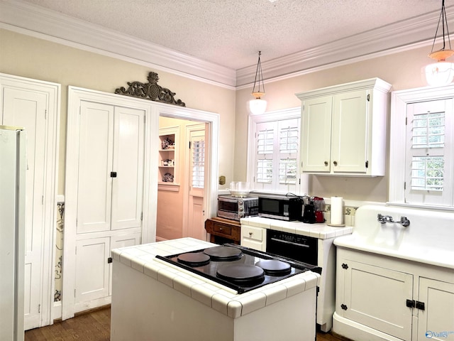102 Jackson St, Albertville, AL 35950 - kitchen with tile countertops, crown molding, white cabinetry, freestanding refrigerator, and plenty of natural light