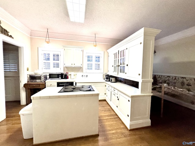 102 Jackson St, Albertville, AL 35950 - kitchen featuring tile countertops, stainless steel microwave, a kitchen island, black cooktop, and white cabinetry