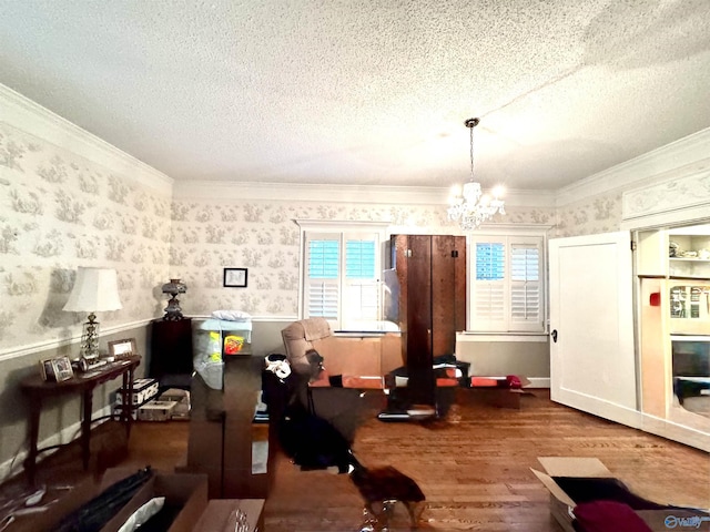 102 Jackson St, Albertville, AL 35950 - workout area featuring wood finished floors, a textured ceiling, a chandelier, wallpapered walls, and crown molding