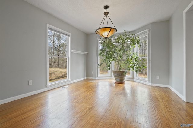 unfurnished room featuring visible vents, baseboards, and hardwood / wood-style floors