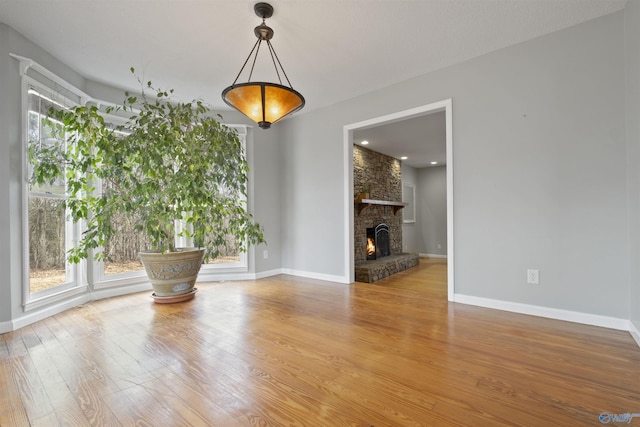 interior space featuring a stone fireplace, wood finished floors, and baseboards