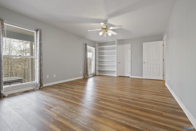 unfurnished bedroom featuring a textured ceiling, a ceiling fan, baseboards, and wood finished floors