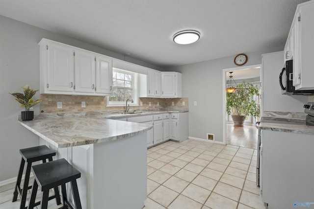 kitchen featuring a sink, stainless steel range oven, backsplash, a peninsula, and white cabinets