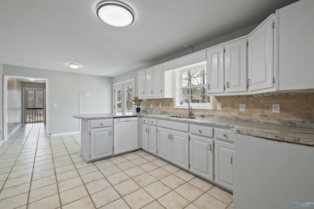 kitchen featuring backsplash, a peninsula, white dishwasher, white cabinetry, and a sink