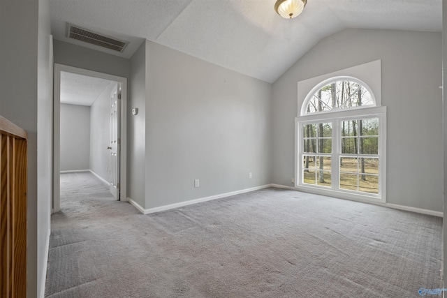 empty room with visible vents, baseboards, lofted ceiling, and carpet