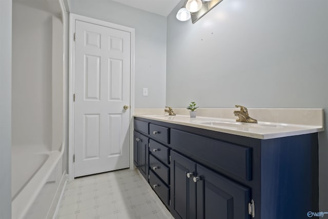 bathroom with tile patterned floors, double vanity, a tub, and a sink