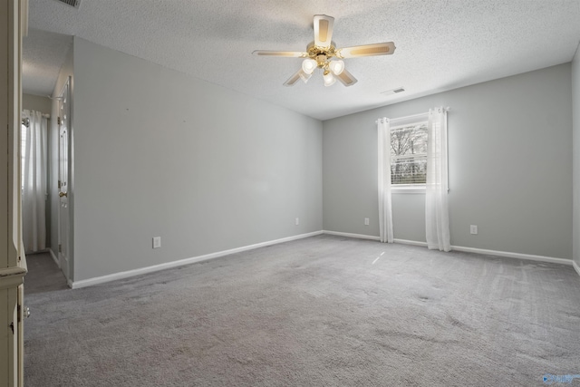 carpeted empty room with visible vents, baseboards, a textured ceiling, and a ceiling fan