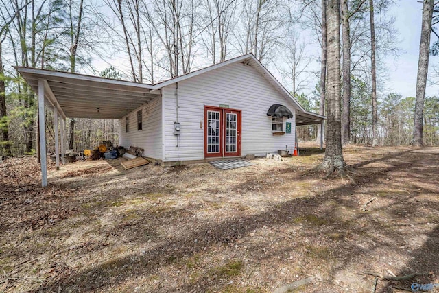 view of front of house with an attached carport, french doors, and dirt driveway