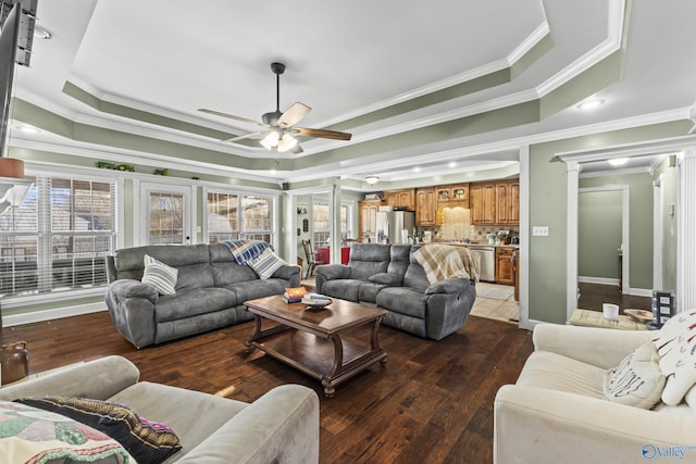 living room with hardwood / wood-style floors, a raised ceiling, and ornate columns