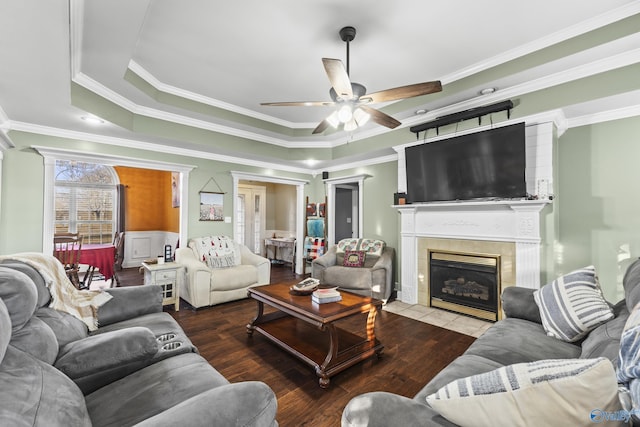 living room with a fireplace, a tray ceiling, wood-type flooring, and ornamental molding