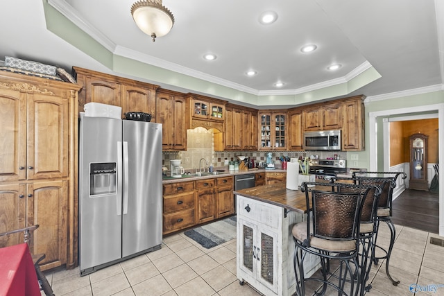 kitchen with sink, a kitchen breakfast bar, a center island, light tile patterned floors, and stainless steel appliances