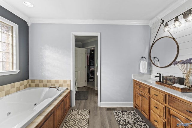 bathroom featuring hardwood / wood-style flooring, a tub to relax in, ornamental molding, and vanity