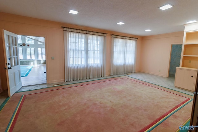 interior space with a textured ceiling, a healthy amount of sunlight, and light tile patterned flooring