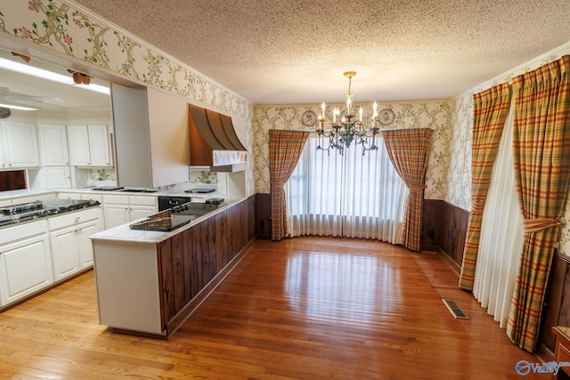 kitchen with white cabinetry, light hardwood / wood-style flooring, a textured ceiling, and kitchen peninsula