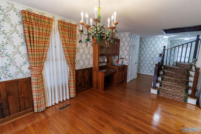 dining space with hardwood / wood-style floors, a textured ceiling, and a notable chandelier