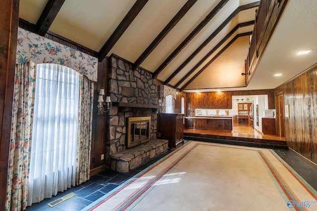 unfurnished living room featuring vaulted ceiling with beams, a fireplace, and wood walls