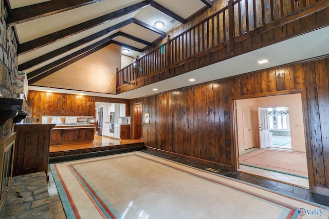 interior space featuring beamed ceiling, high vaulted ceiling, and wood walls