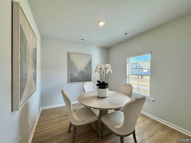 dining area with baseboards, visible vents, and wood finished floors