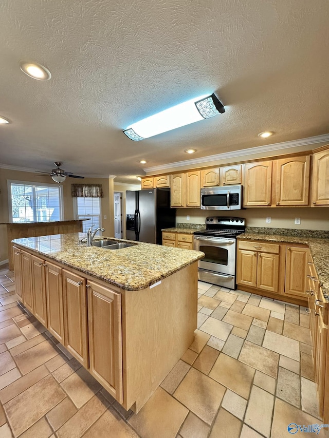 kitchen with sink, appliances with stainless steel finishes, ornamental molding, light stone countertops, and a center island with sink