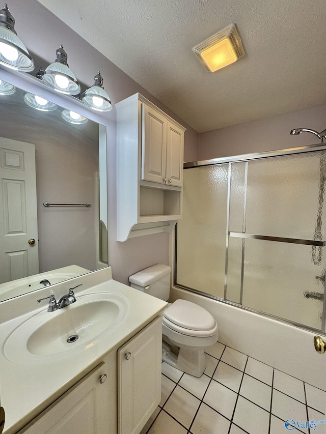 full bathroom with tile patterned floors, toilet, combined bath / shower with glass door, a textured ceiling, and vanity