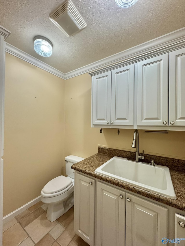 bathroom with vanity, a textured ceiling, ornamental molding, and toilet