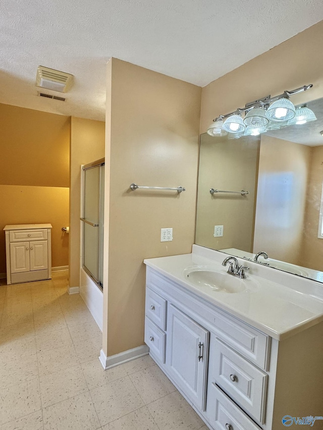 bathroom featuring vanity, bath / shower combo with glass door, vaulted ceiling, and a textured ceiling