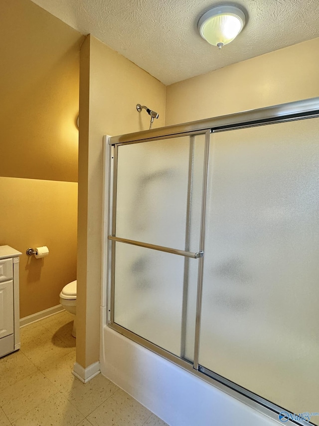 bathroom featuring a textured ceiling, toilet, and combined bath / shower with glass door