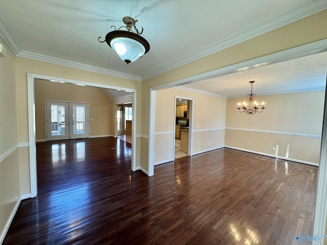 spare room with crown molding, dark hardwood / wood-style floors, an inviting chandelier, and french doors