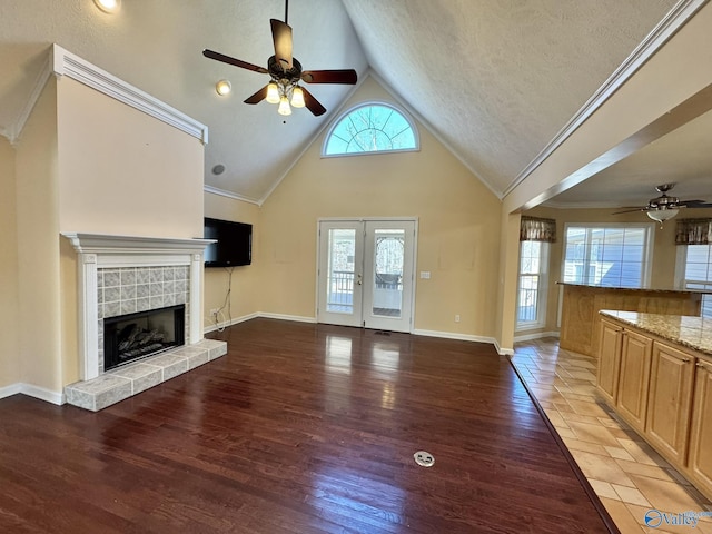 unfurnished living room featuring crown molding, hardwood / wood-style floors, a tile fireplace, and french doors