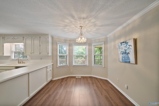2010 Burlington Dr SE, Huntsville, AL 35803 - unfurnished dining area with dark wood-type flooring, a textured ceiling, a chandelier, and ornamental molding