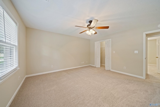 2010 Burlington Dr SE, Huntsville, AL 35803 - unfurnished bedroom featuring multiple windows, light colored carpet, a ceiling fan, and a walk in closet