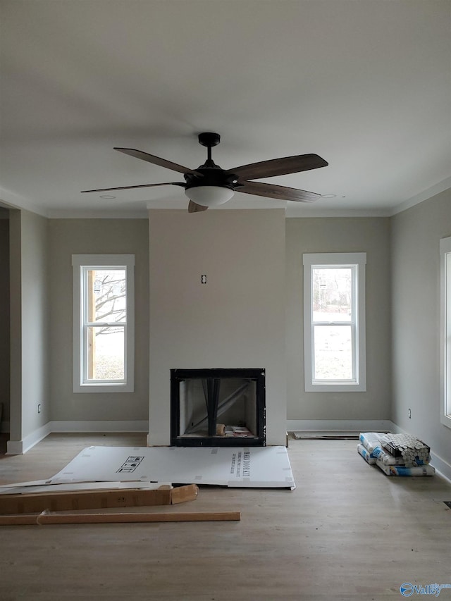 unfurnished living room featuring ceiling fan, ornamental molding, and light hardwood / wood-style floors