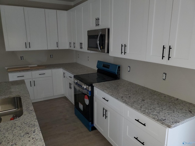 kitchen with light wood-type flooring, stainless steel appliances, white cabinetry, and light stone counters