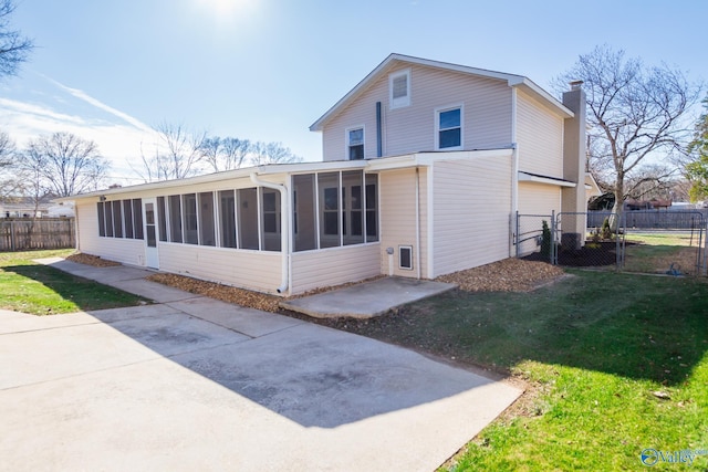 back of house with a yard, a patio area, and a sunroom