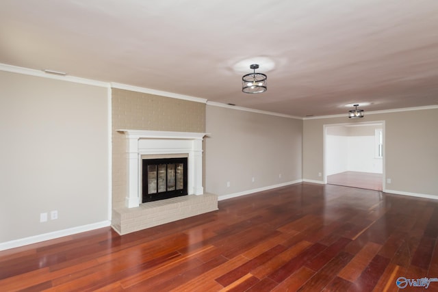 unfurnished living room with ornamental molding, a brick fireplace, and dark hardwood / wood-style flooring